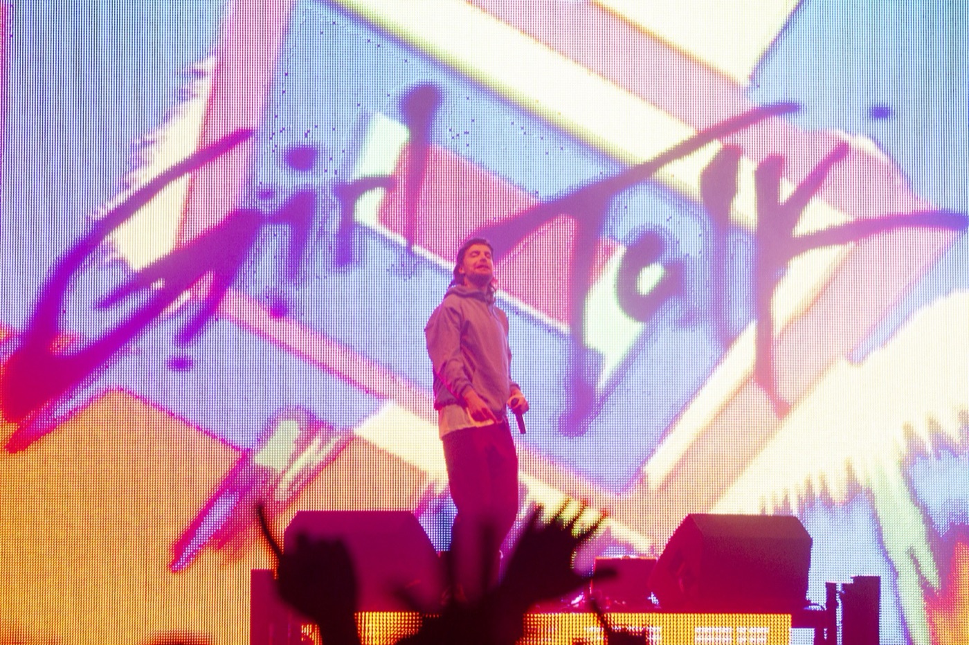 Girl Talk stands with a microphone in front of a pink and purple Girl Talk logo on the video wall.